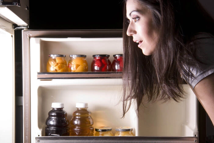 Frau guckt in den Kühlschrank