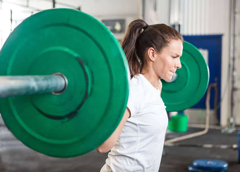 woman lifting heavy weights - strength training for body definition