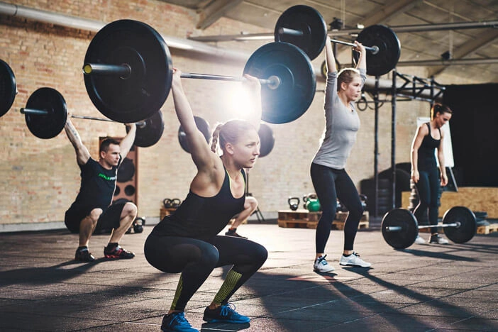 people in a fitness class lifting heavy weights