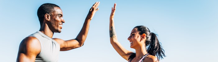 man and woman in sportswear on top of a mountain giving a high five