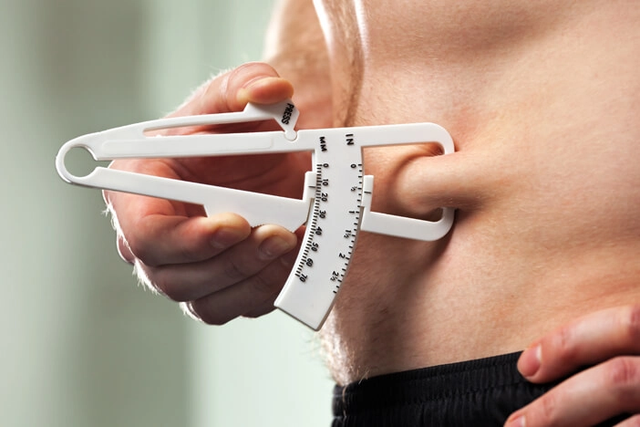 man measuring his body fat with a fat caliper