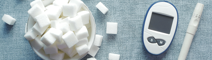 Blutzuckermessgerät neben Zuckerwürfeln